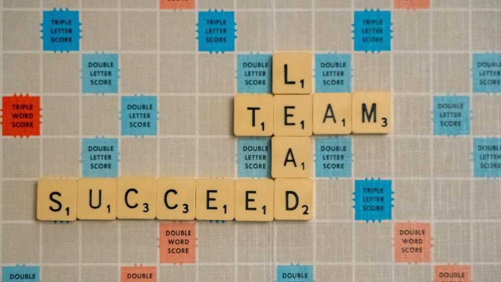 Fichas de Scrabble formando las palabras “Lead”, “Team” y “Succeed” sobre un tablero