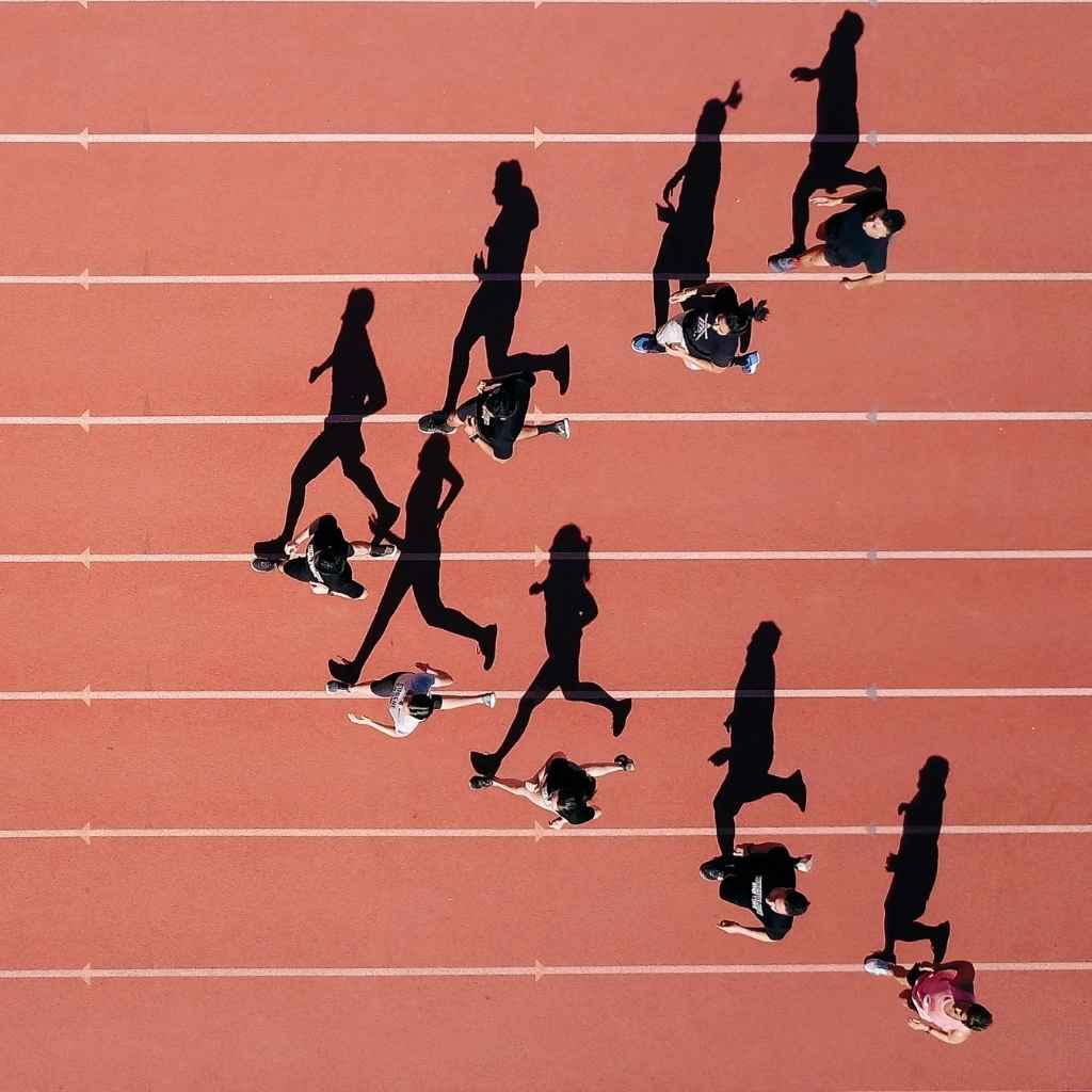 Vista cenital de varias personas corriendo en una pista, proyectando largas sombras alineadas